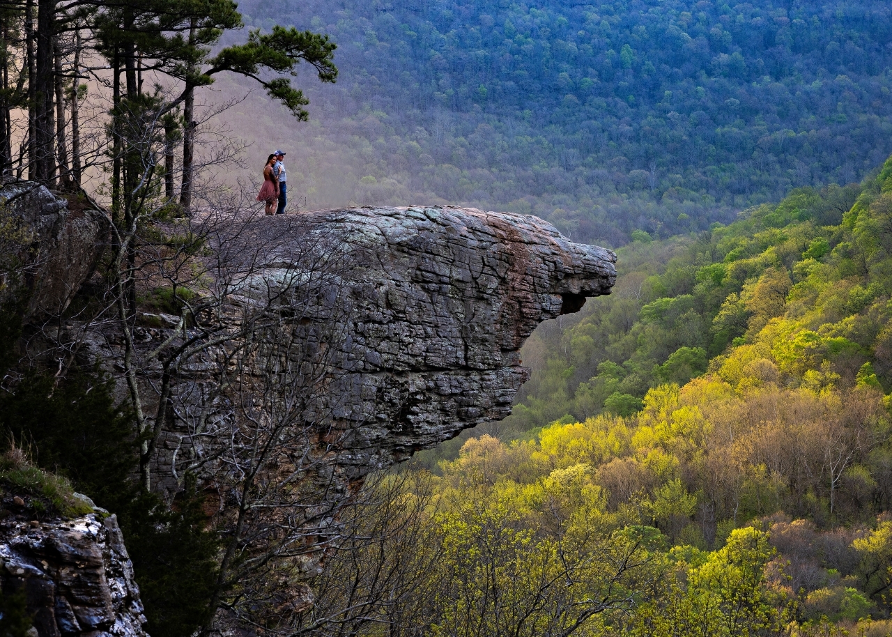 Couple look out over the mountains and valley of the Buffalo National River on top of Hawksbill Crag in Arkansas